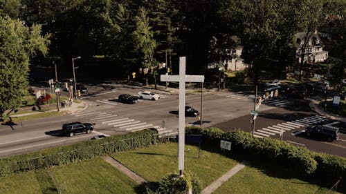 A White Cross Marker In The Corner Lot Of An Intersecting Road