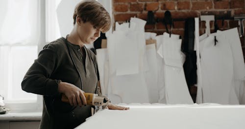 A Woman Cutting Cloth Using A Fabric Cutter Machine