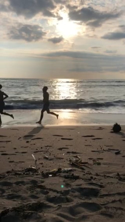 Two Persons Running Along The Seashore