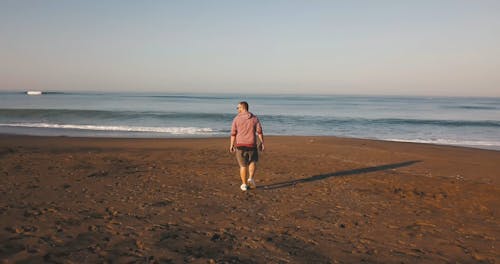 An Aerial Footage of a Man Walking in the Beach