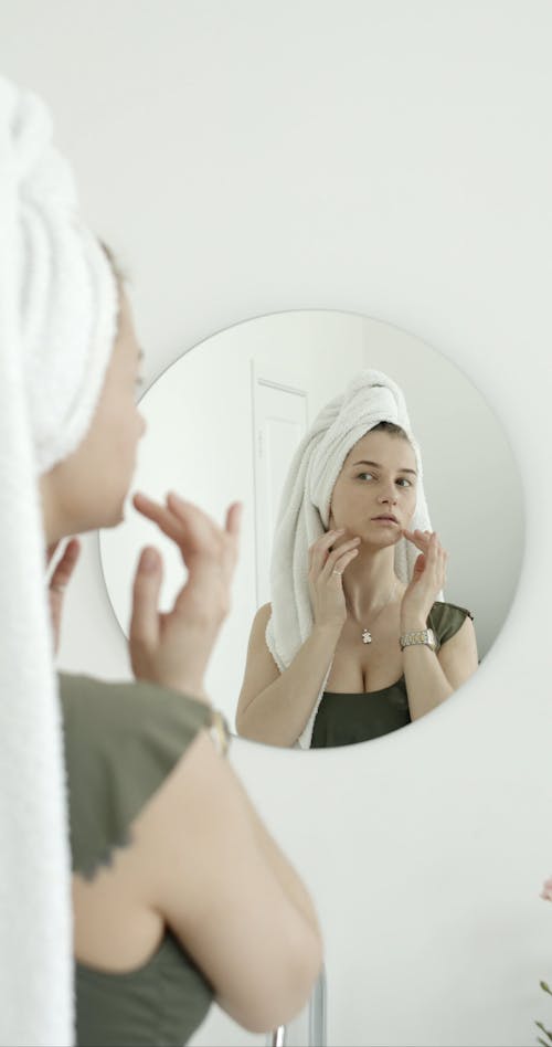 Woman Massaging Her Face Infront Of A Mirror