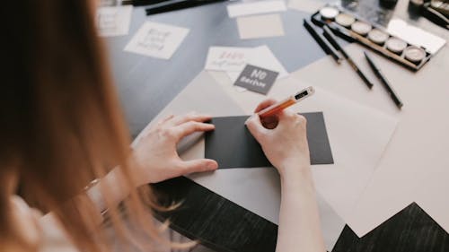 Person Writing on a Paper with a Pen