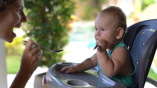 Mother Doing Facial Expressions While Feeding Her Baby 