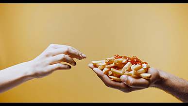 two hands reaching for a plate of food