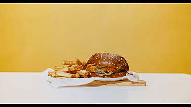 a burger and fries on a plate in front of a yellow wall