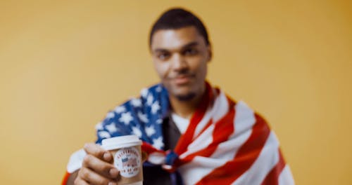 Man With an American Flag Holding a Paper Cup