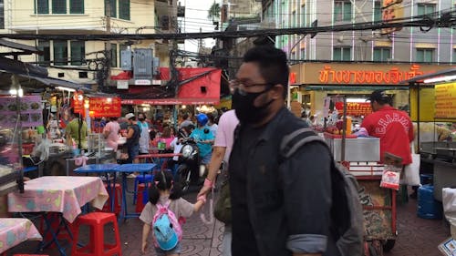 People Walking on a Street With Food Stalls