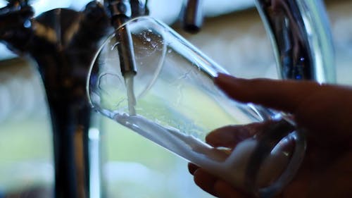 Close-Up View of Person's Hand Holding a Drinking Glass With Draft Beer