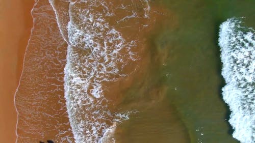 An Aerial Footage of Waves Crashing on the Seashore