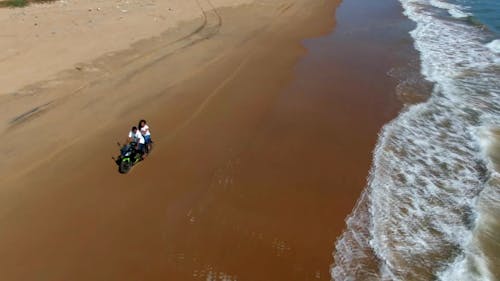People On A Motorbike Driving Along The Seashore