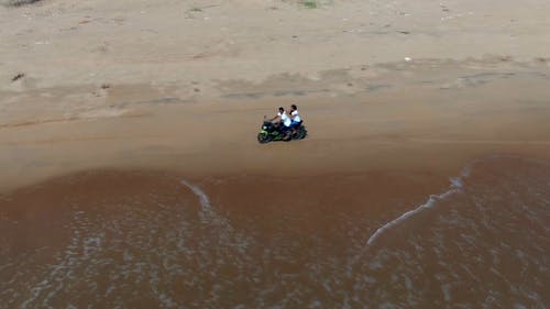 People On A Motorbike Driving Along The Shore