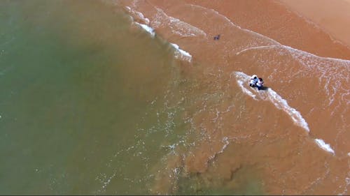 Drone Footage of Two Person Standing on Beach Shore