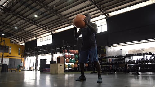 Man Squatting While Holding a Medicine Ball