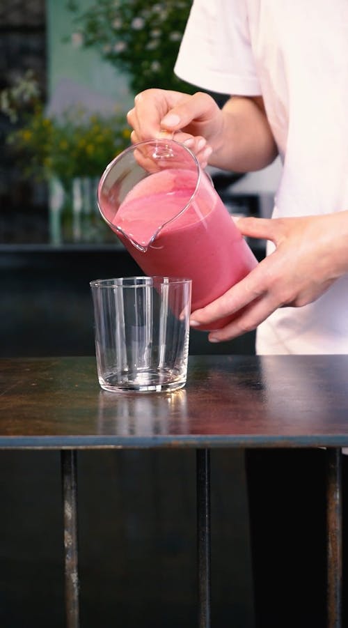 Man Pouring Strawberry Milkshake Into A Glass