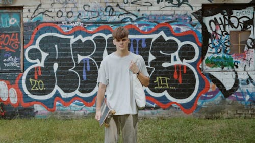 A Young Man Carrying a Tote Bag and a Skateboard