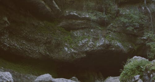 A Couple Enjoying The View Of A Waterfall From The Rock Cliff