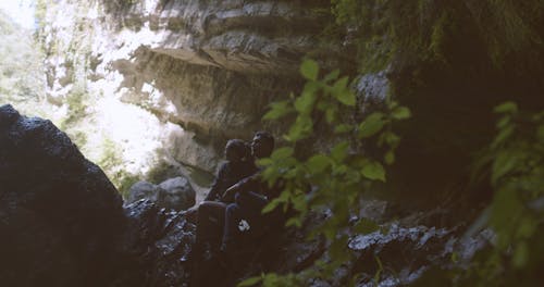 A Backpacking Couple Resting On Shaded Rocks