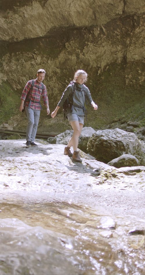 A Couple Checking A Brook Flowing Through Rocks