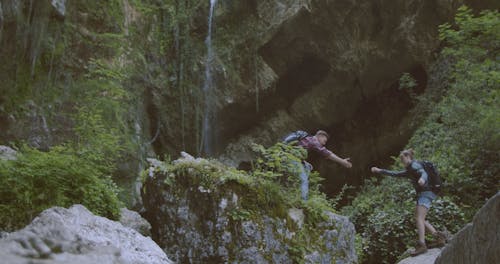 A Couple Successfully Reaching The Top And Looking At A Waterfalls