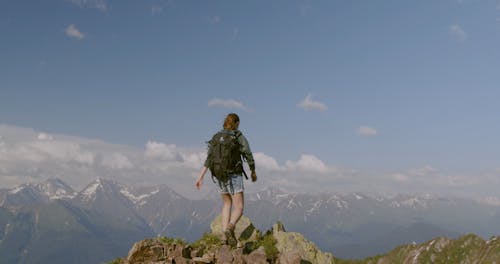 Woman Standing At The Peak Of A Rocky Mountain