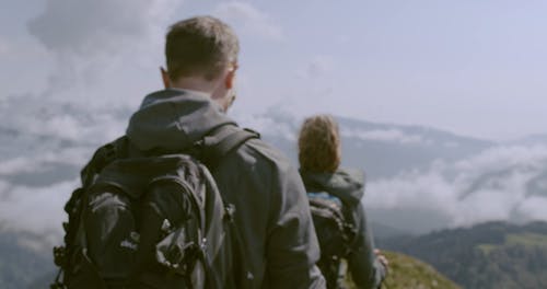 A Couple Walking Towards The Mountain Edge