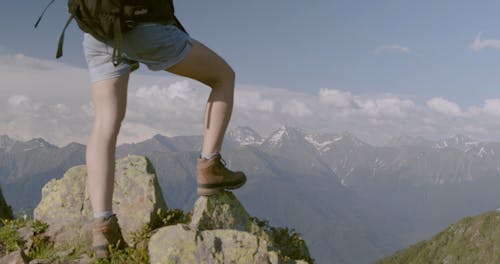 A Person Standing On Rocks Atop A Mountain