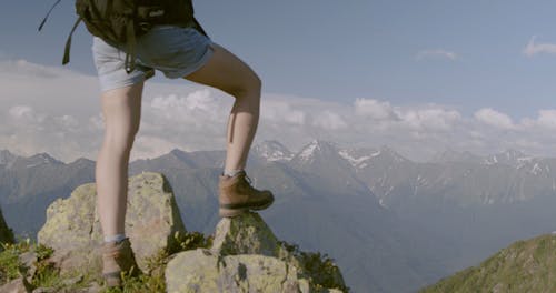 A Person Standing On Rocks Atop A Mountain