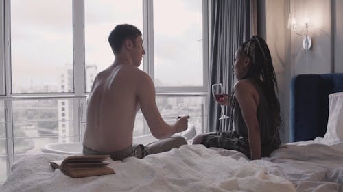 Couple Sitting on Bed While Drinking Wine