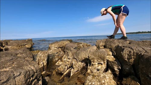 Woman Exploring Rocks On The Beach