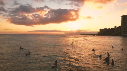 Surfers On The Beach In Hawaii At Sunset