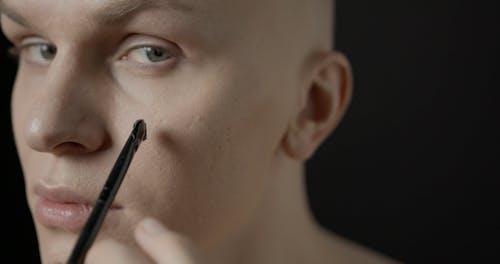 A Man Painting His Face With Black Lines