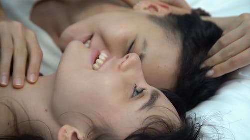 Couple Lying Down on Bed While Talking to Each Other