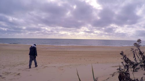 A Man Walking Towards The Beach