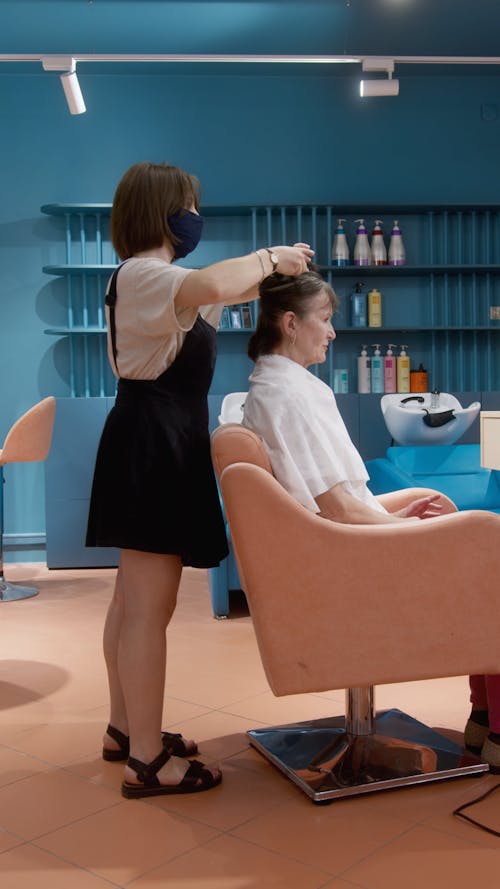 Woman Sitting on Orange Chair While Getting Her Hair Done