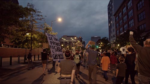 People Walking on Street While Holding Posters