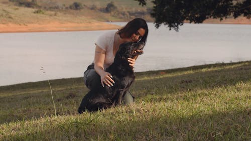 Woman Petting Her Dog on Grass Field
