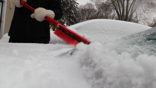 Woman Brushing Off Snow From Her Car