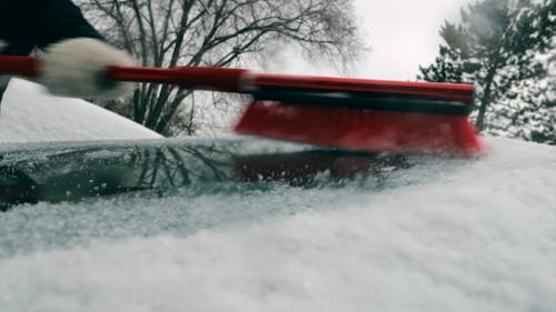 Close-Up View of Person Brushing Off Snow From His Car