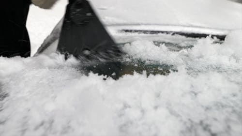 Close-Up View of Person Removing Snow From His Car