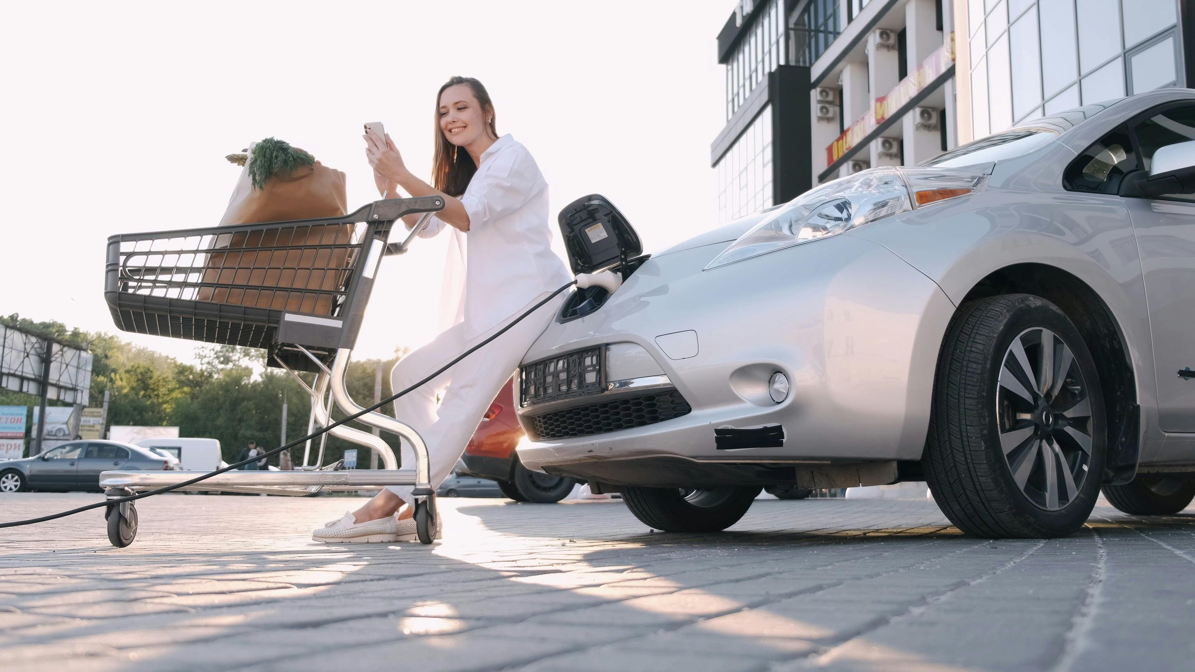 A Woman Waiting For Her Electric Car To Be Charged · Free Stock Video