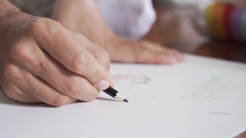 Close-Up View of Person Drawing Using Black Pencil