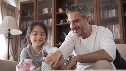 Dad and Daughter Having Fun Playing With Toy Animals