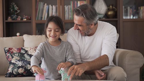 Dad and Daughter Having Fun Playing With Animal Toys