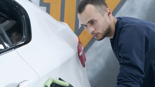 Man Wiping the White Car With Green Cloth