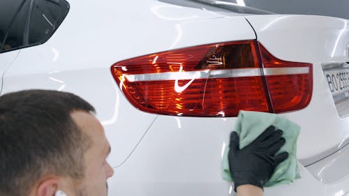 Man Wiping the White Car With Cloth