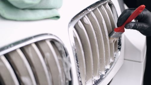 Person Cleaning the Car Grille With Brush