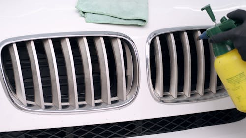 Person Spraying Water on Car Grille