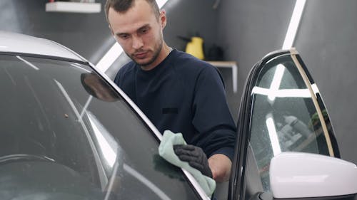 Man Wiping the White Car With Green Cloth