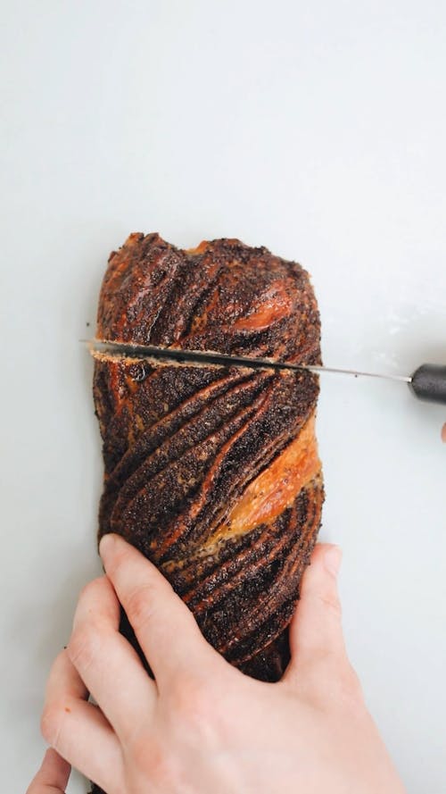 Person Slicing a Bread Using a Knife