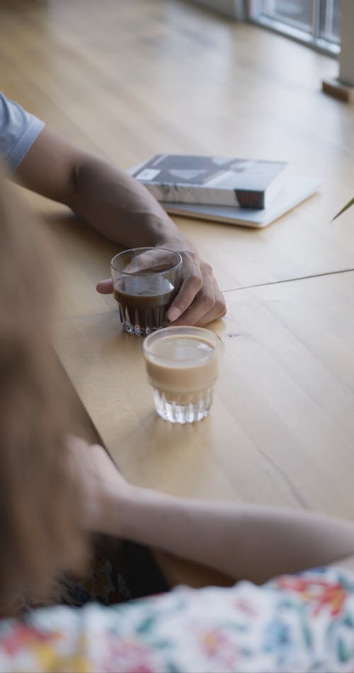 Two Persons Sitting by the Table While Drinking Their Coffee